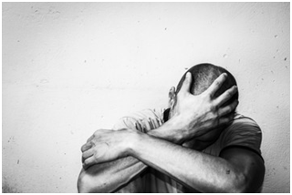 Homeless man drug and alcohol addict sitting alone and depressed on the street feeling anxious and lonely, social documentary concept black and white